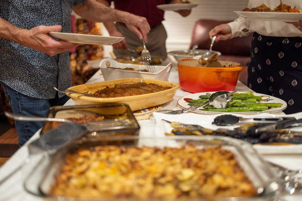 Family gathered around a Thanksgiving potluck dinner